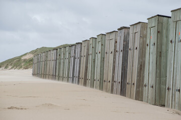 Row of small wooden buildings on beach near the coast. Seaside shed leisure background. Perspective to the right.