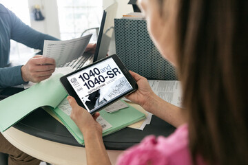 Taxes: Woman Uses Tablet To Find 1040 Tax Instructions