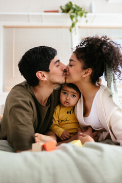Indian couple with baby kissing on bed