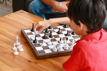 Father and son playing chess at home, closeup