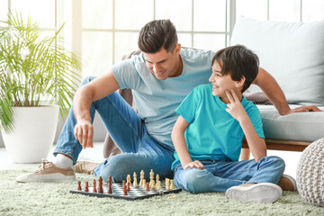 Father and son playing chess at home - obrazy, fototapety, plakaty