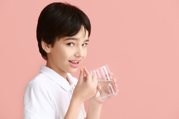 Little boy taking fish oil pill on color background