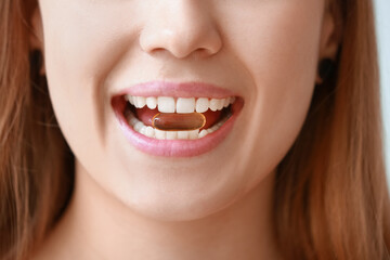 Obraz premium Young woman taking fish oil pill, closeup