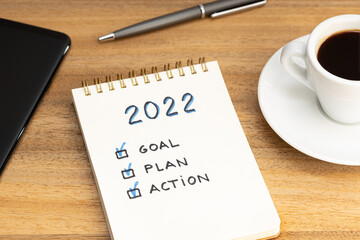 New year 2022 goal, plan, action text on notepad and coffee cup and smartphone on wooden desk. Business motivation concept