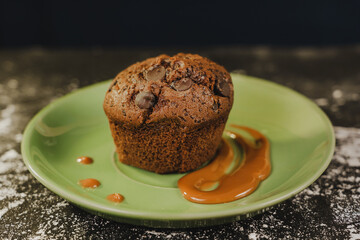 Homemade chocolate chips muffin with caramel on a green dish served gourmet