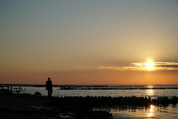 Fototapeta na wymiar Sunset on the sea/ man staying in the calm water of the sea.