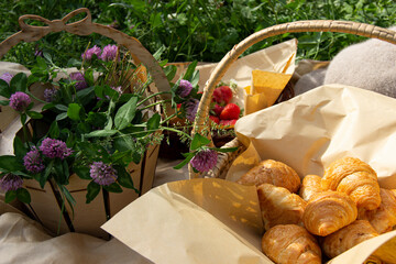 morning picnic outside.there is a strawberry ,croissantin the basket and flowers