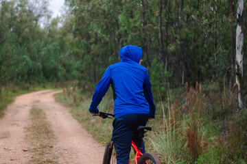 Young man riding a bike on a forest road, playing sports in nature, active lifestyle.