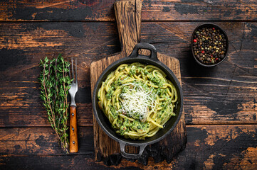 Spaghetti Pasta with pesto sauce, spinach and parmesan in a pan. Dark Wooden background. Top view