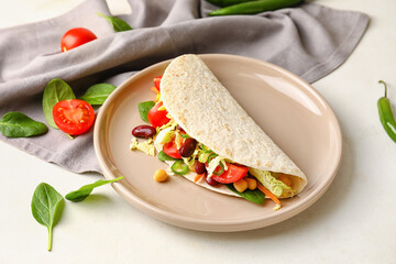 Plate with tasty vegetarian taco on light background
