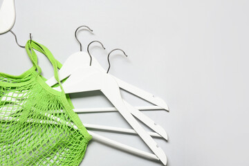 Stylish eco bag and clothes hangers on light background