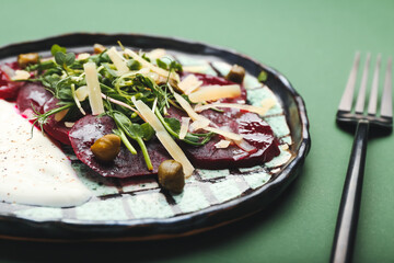 Plate with delicious beetroot carpaccio on color background, closeup