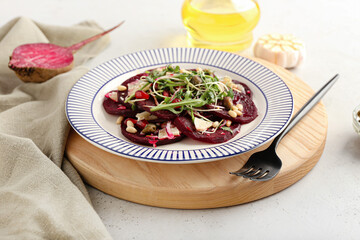 Plate with delicious beetroot carpaccio on light background