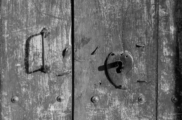 Puerta de madera de antaño con chapa de metal en forma de corazon y jalador