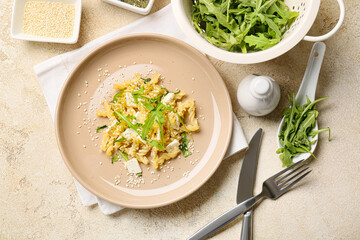 Plate with tasty pasta and ingredients on light background