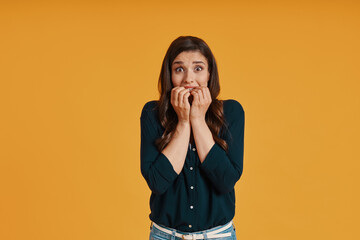 Shocked young woman in casual clothing covering mouth with hands