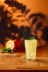 Wooden table in a tropical shade at sunset and a cold drink with oranges 