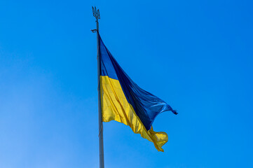 The big national flag of Ukraine flies in the blue sky