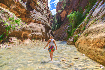 Woman walking through a river in the bottom of a canyon