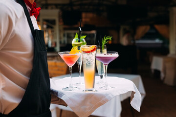 The waiter serves cocktails on a tray.