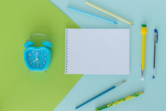 school supplies. The concept of education. Everything for school and office. Pens, pencils, notepad, alarm clock and everything for studying on a blue-green background. Flat. Mock up.