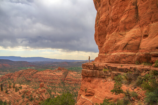 Woman standing on a cliff next to red rocks