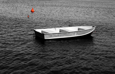 Single boat floating in the sea in black and white