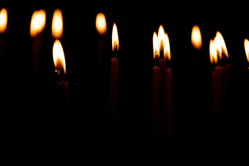 close up a lot of burning candles isolated on black background.