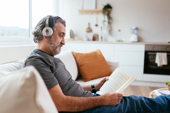 Bearded male enjoying reading on settee