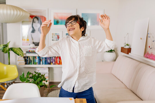 Happy Pre-teen with braces dancing in colorful room by bookshelves and wall gallery