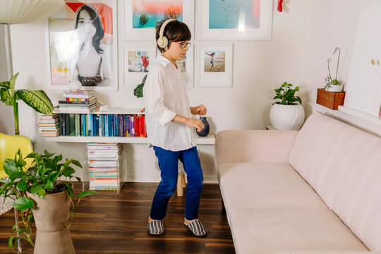 Teen Boy dancing and singing by colorful  books and wall gallery