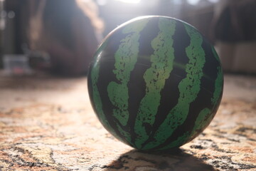 Inflatable rubber ball in the form of a watermelon at home on the floor close-up