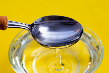 Sugar syrup in glass bowl on yellow background.