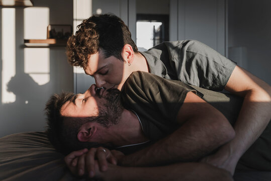 Same sex couple kissing lying on the bed.