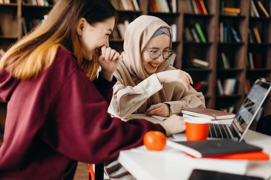 Laughing Diverse Students Using Laptop In Library