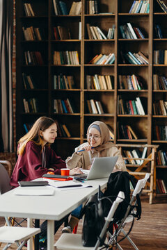Cheerful diverse girlfriends studying together in classroom