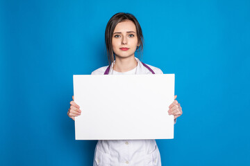 Fototapeta premium medical doctor woman smile hold blank card board on blue background