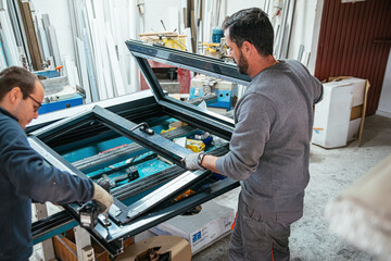 Male workers assembling aluminum window at factory