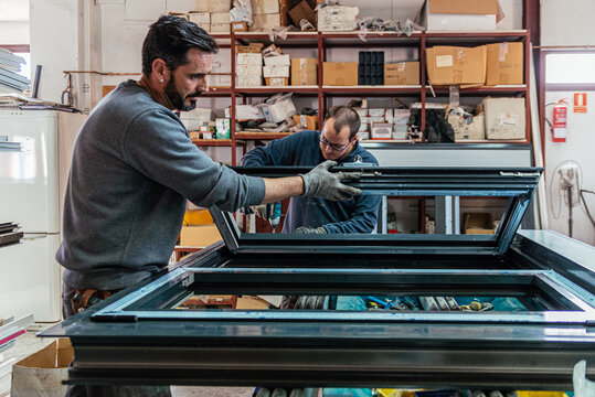 Male workers assembling aluminum window at factory
