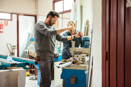 Male workers using drilling machine at factory