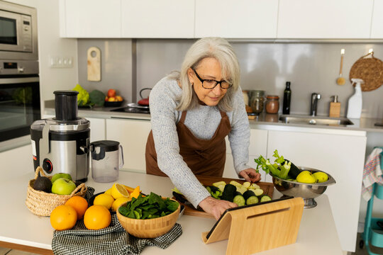 mature woman browsing table standing on kitchen