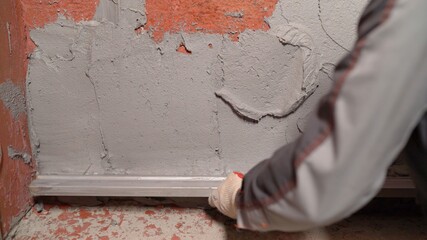 A worker uses a construction tool to level mortar on the wall. Builders use cement plaster to level the wall. Leveling the wall from mortar.