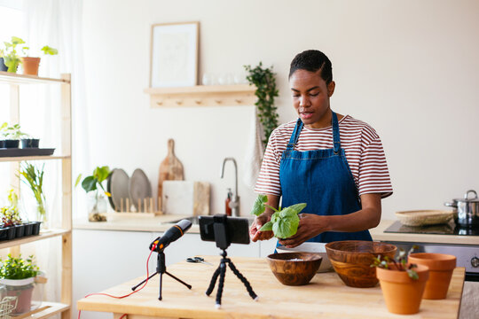 Black woman showing green plant to vlog audience
