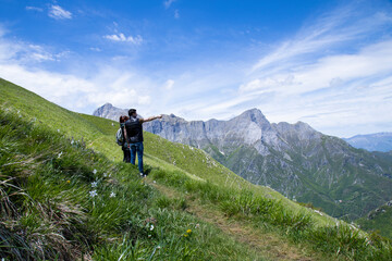 pair of man and woman in flowered mountains of Italian Alps look into the distance