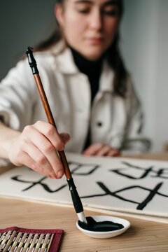 Young woman writing japanese kanji characters with a brush and ink