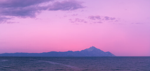 Scenic sunrise at Sarti beach, Halkidiki, Sithonia, Greece, Europe. Golden sunrise over the mountain Athos, dramatic morning seascape of the Aegean sea.