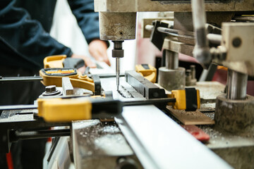 Master using drilling machine in workshop