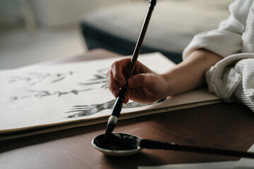 Young woman writing japanese kanji characters with a brush and ink