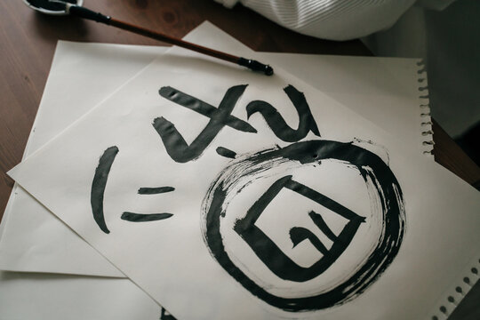 Young woman writing japanese kanji characters with a brush and ink