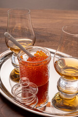 Pairing of single malt scotch or japanese whisky and salted red trout fish caviar in glass jar